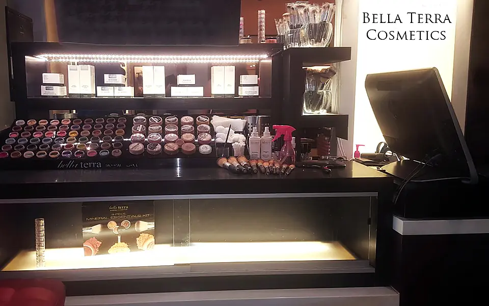 Lit BELLATERRA Cosmetics kiosk counter with rows of mineral makeup, 2016